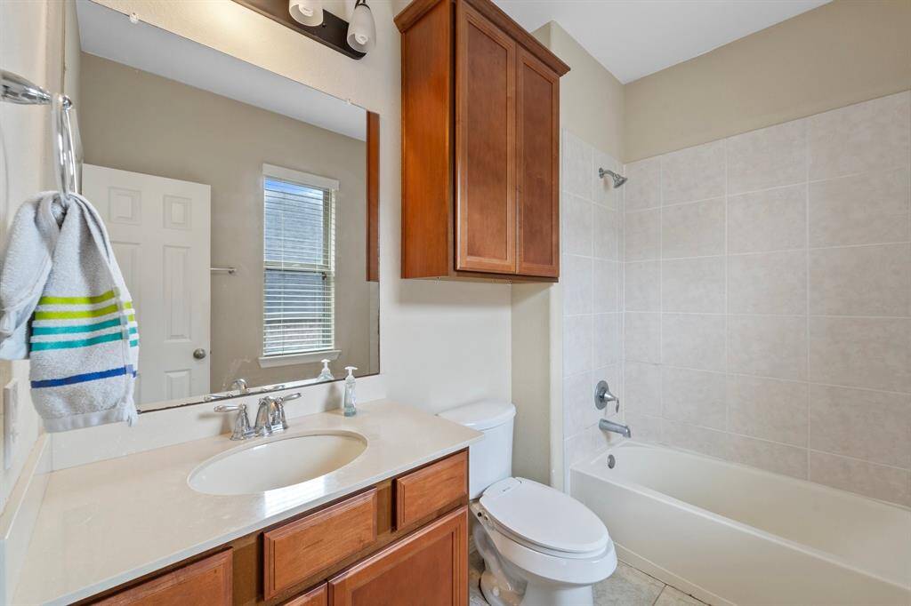 Features a tiled shower/tub combo, extended vanity, and upper cabinetry for additional storage.