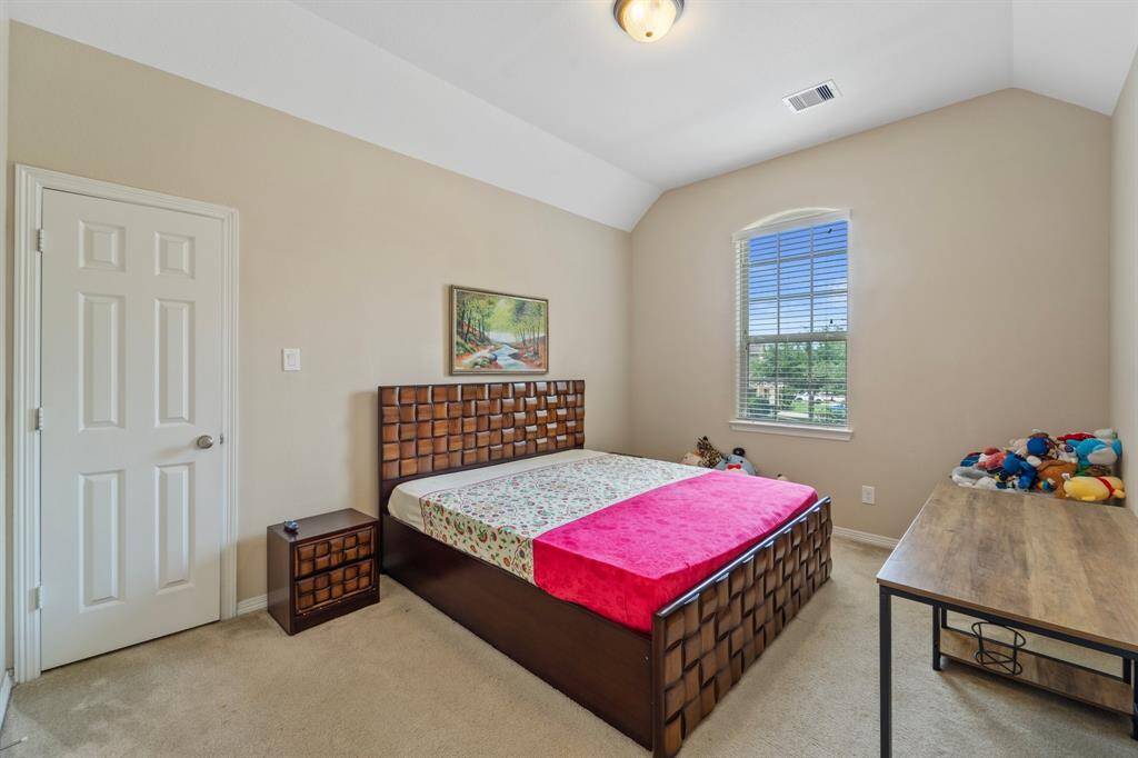 This bedroom boasts vaulted ceilings and a front-facing window for soft natural light.