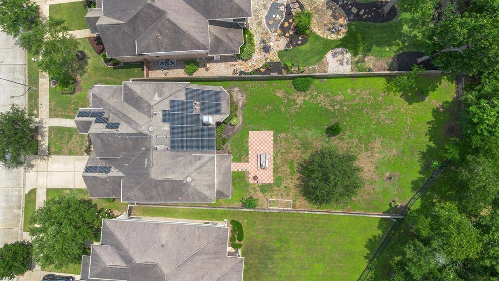 Aerial view highlights the expansive backyard and spacious lot with no back neighbors, along with energy-saving solar panels already installed on the roof.