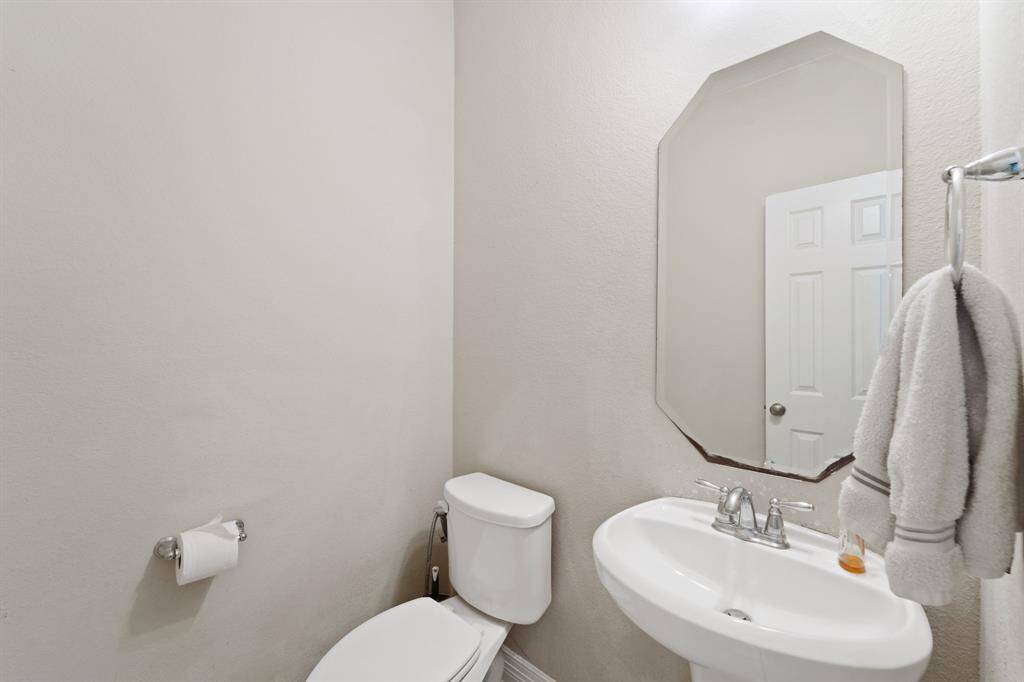 Conveniently located half bath with pedestal sink and neutral tones—ideal for guests.