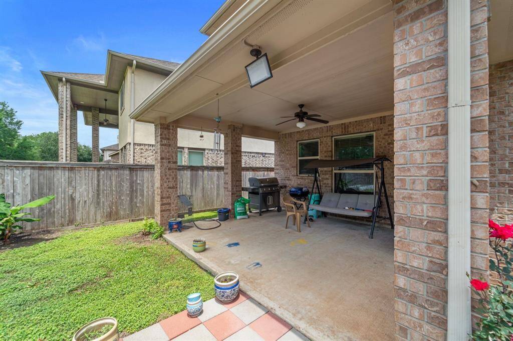 Spacious covered patio with ceiling fan, ideal for grilling, lounging, or enjoying outdoor dining year-round.