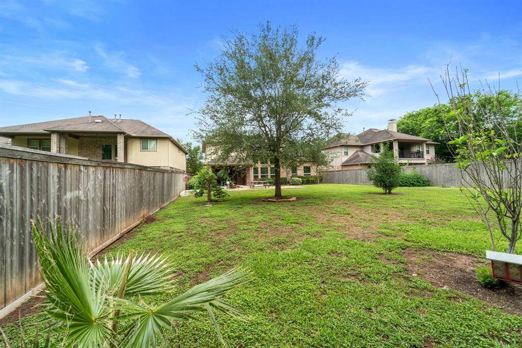 A mature tree anchors this generously sized backyard, providing shade and a scenic backdrop.