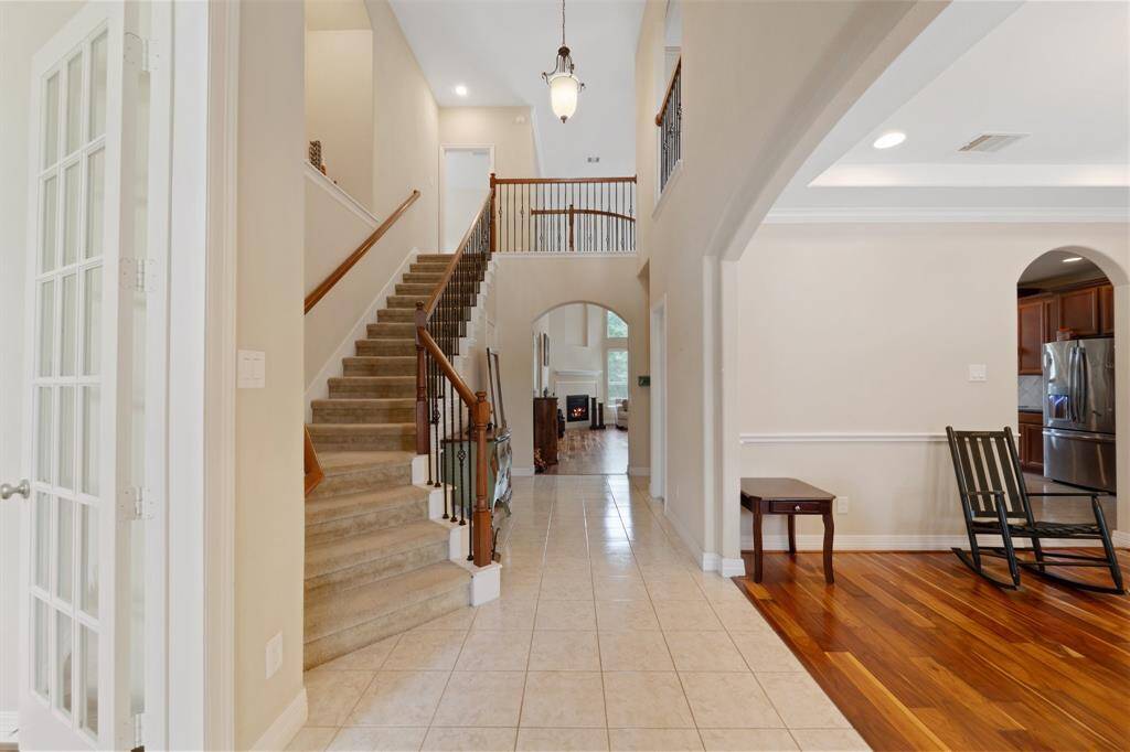 Grand two-story foyer with elegant staircase and tile flooring offers a warm first impression and seamless flow into the heart of the home.