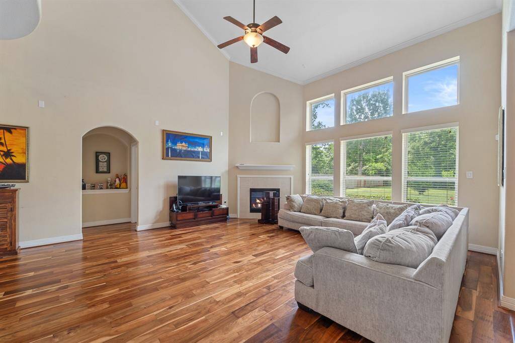 Enjoy serene backyard views through expansive windows in the living room, complemented by rich wood flooring and a cozy fireplace.