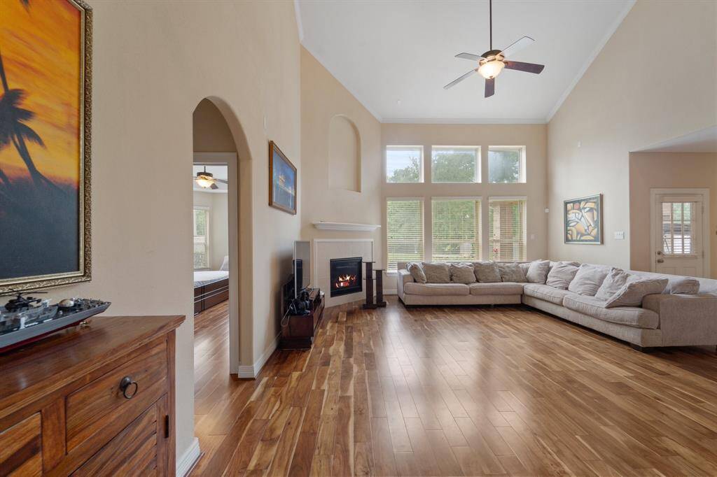Stunning living room with soaring ceilings, gas fireplace, and a wall of windows bringing in abundant natural light.
