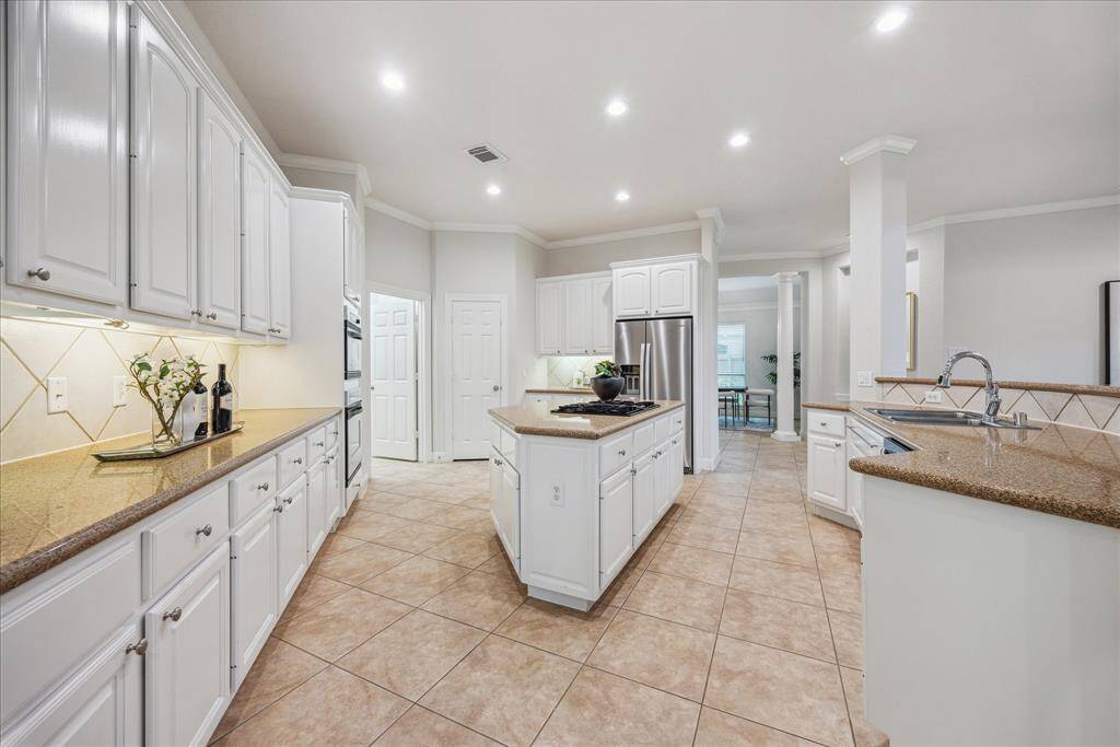 Well-appointed kitchen with under-cabinet lighting, a spacious island with built-in cooktop, and bright white cabinetry for a clean look.
