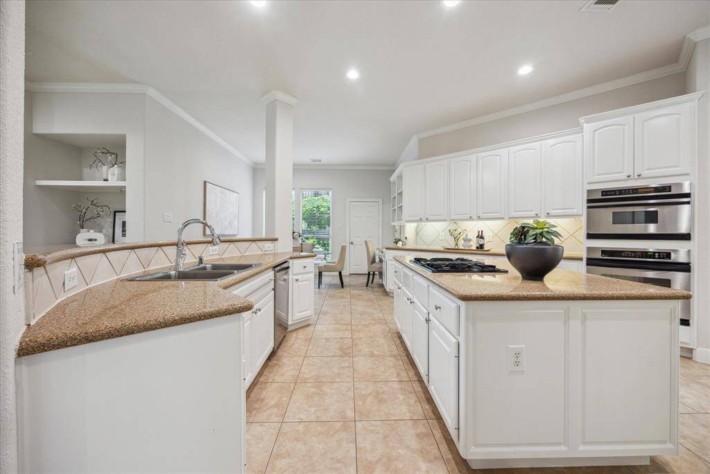Kitchen equipped with stainless steel appliances, a gas cooktop on the island, and ample counter space.