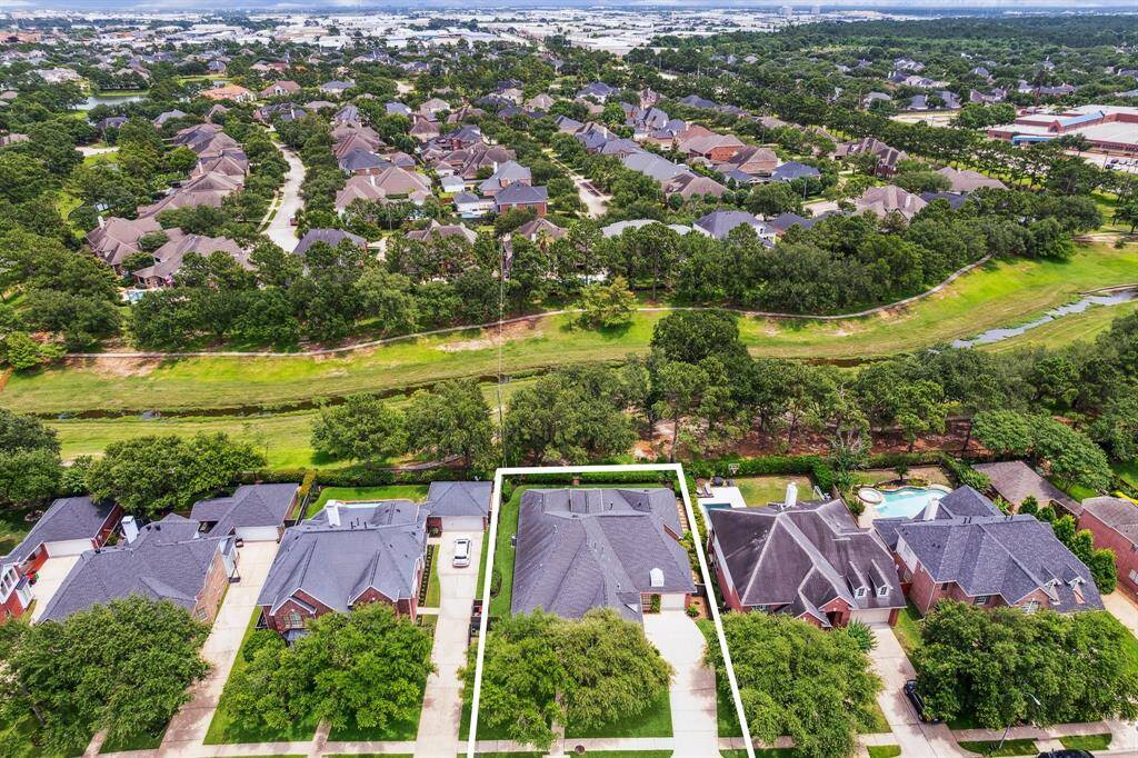 Aerial view showcasing the home’s ideal location on a greenbelt lot, offering added privacy and no rear neighbors in the gated Lakes on Eldridge North community.