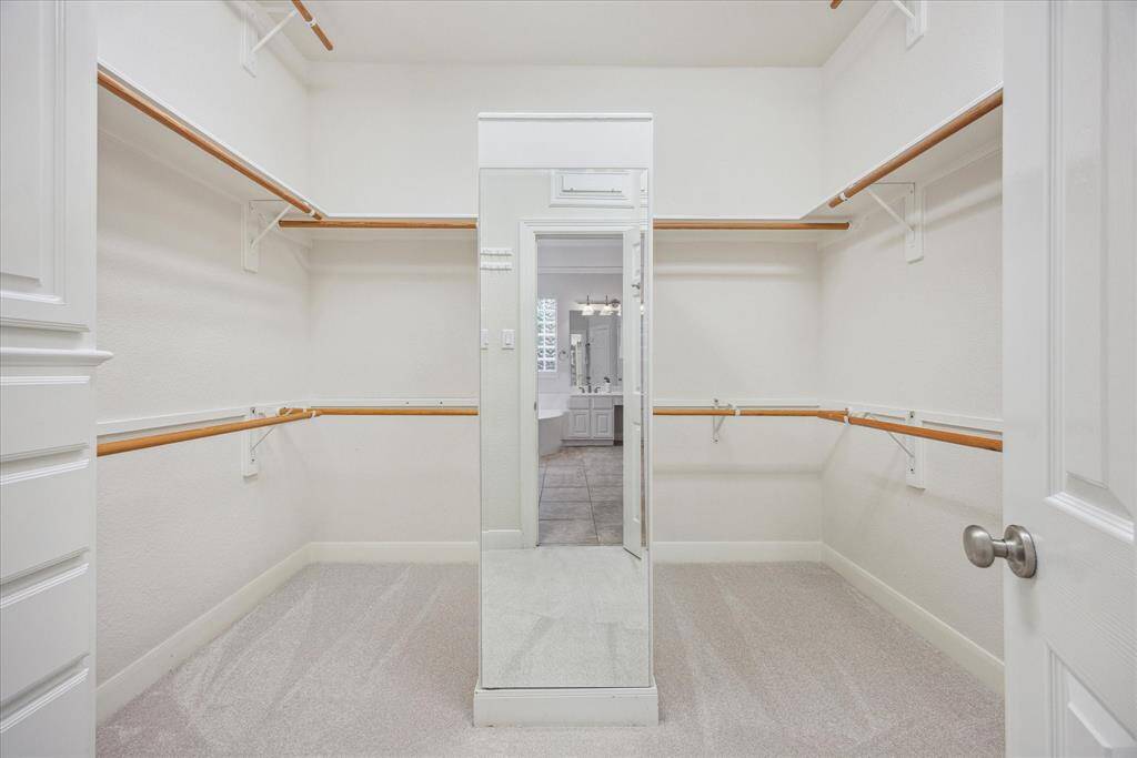 Large walk-in closet with double doors, featuring both upper and lower hanging space for efficient organization.
