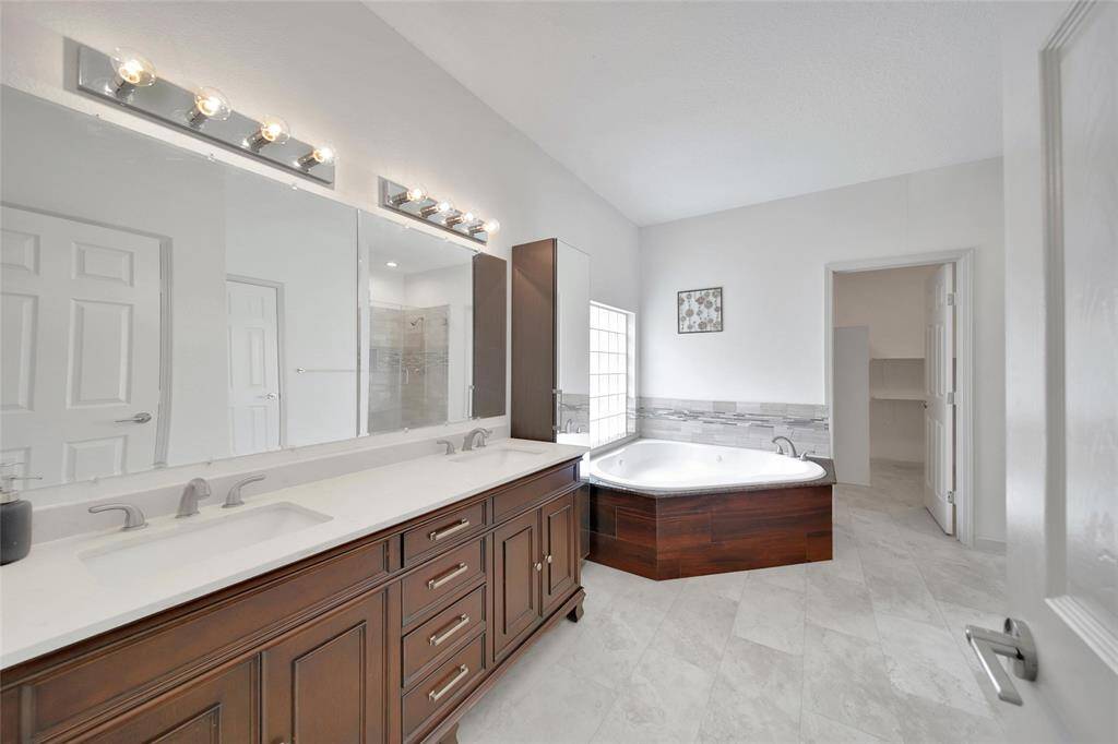The primary ensuite bath boasts a double vanity with quartz top, a storage tower with full-length mirror, an over-sized jetted tub and a frameless glass shower.