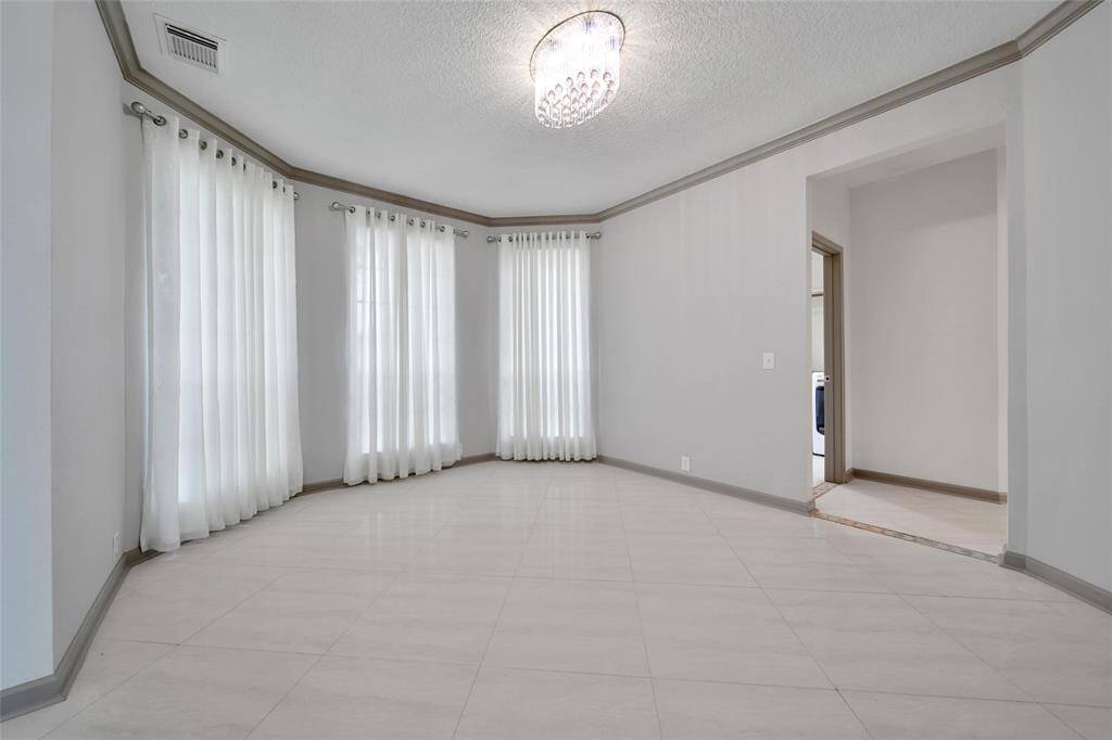 The formal dining room opens to the foyer and the kitchen for ease of entertaining. It features rich crown molding, floor to ceiling windows, and a chandelier for charm.