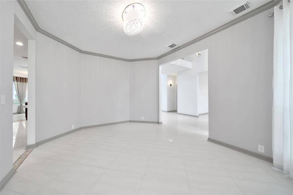 The formal dining room opens to the foyer and the kitchen for ease of entertaining. It features rich crown molding, floor to ceiling windows, and a chandelier for charm.