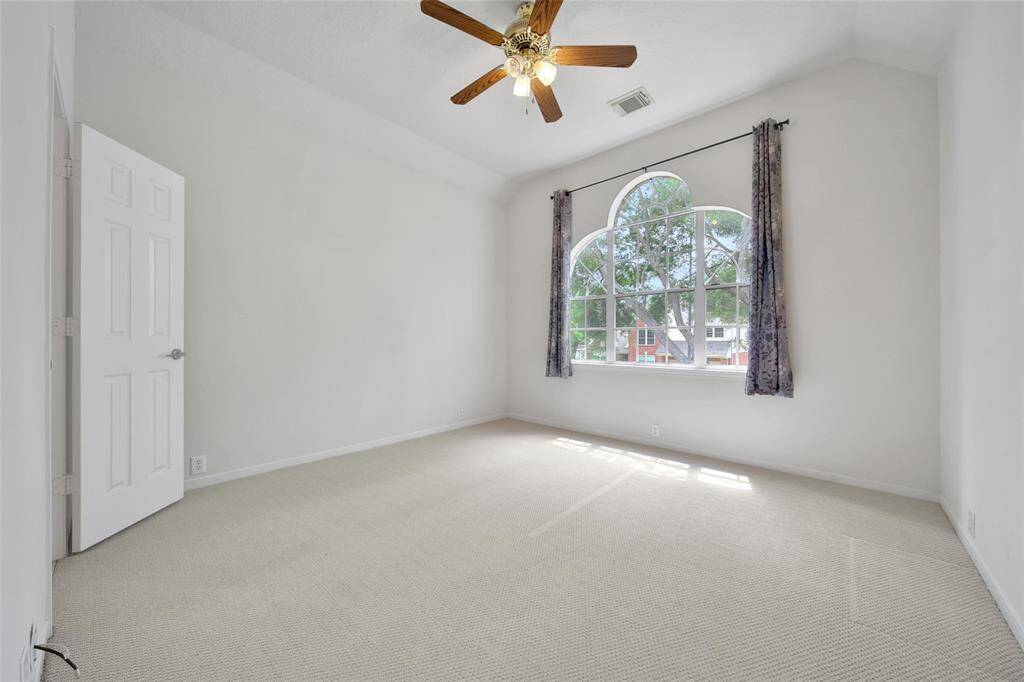 The front bedroom offers neutral paint and carpet, tree-lined views and a ceiling fan for temperature control. It has a Jack and Jill bathroom attached to it.