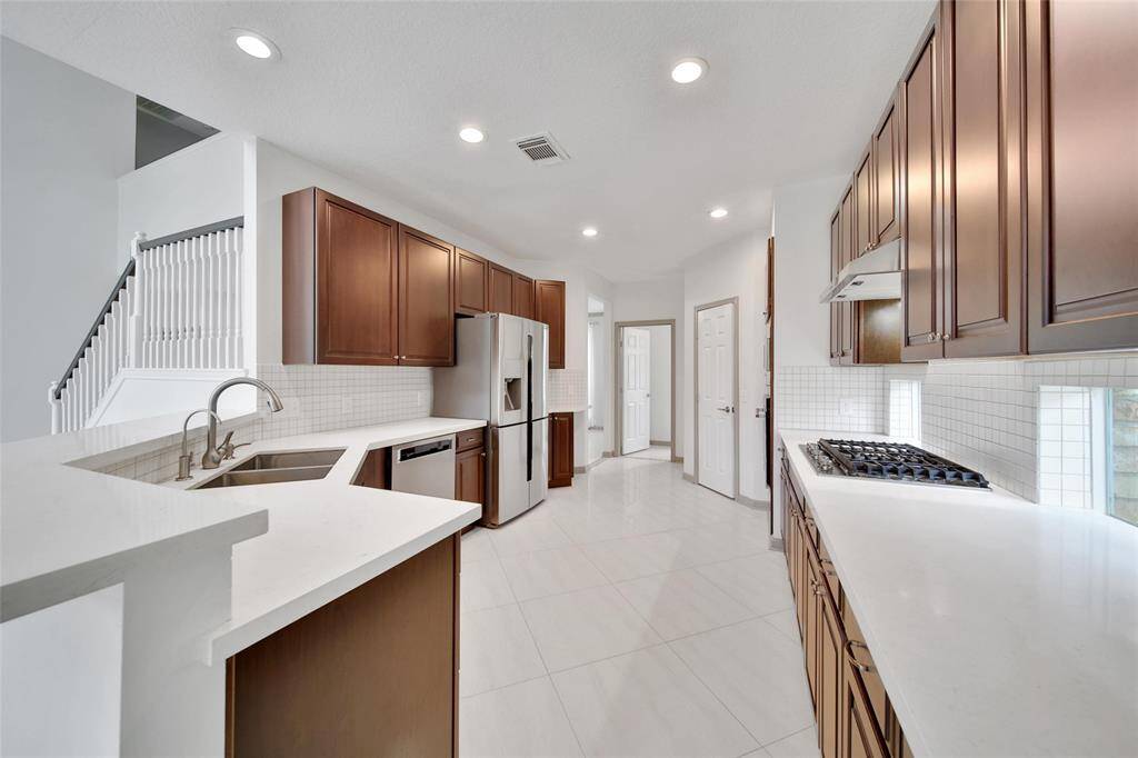 Rich Kraftmaid raised panel cabinetry is offset by gleaming white quartz counters and stainless steel appliances in this impeccably appointed kitchen.