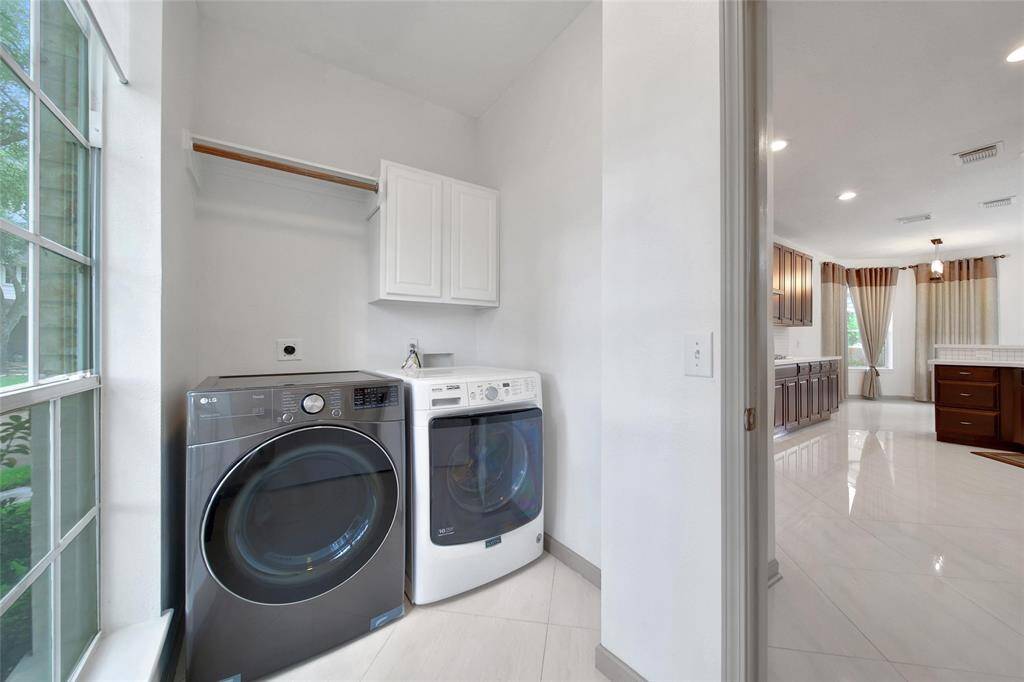 The utility room is conveniently located at the back of the kitchen and comes complete with a front load washer and dryer, hanging rod and storage cabinet.