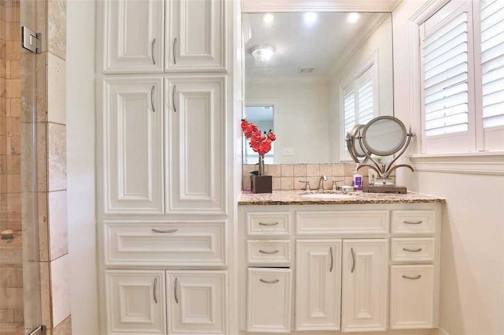 Wonderful cabintry with hamper and granite countertop in your primary bathroom.