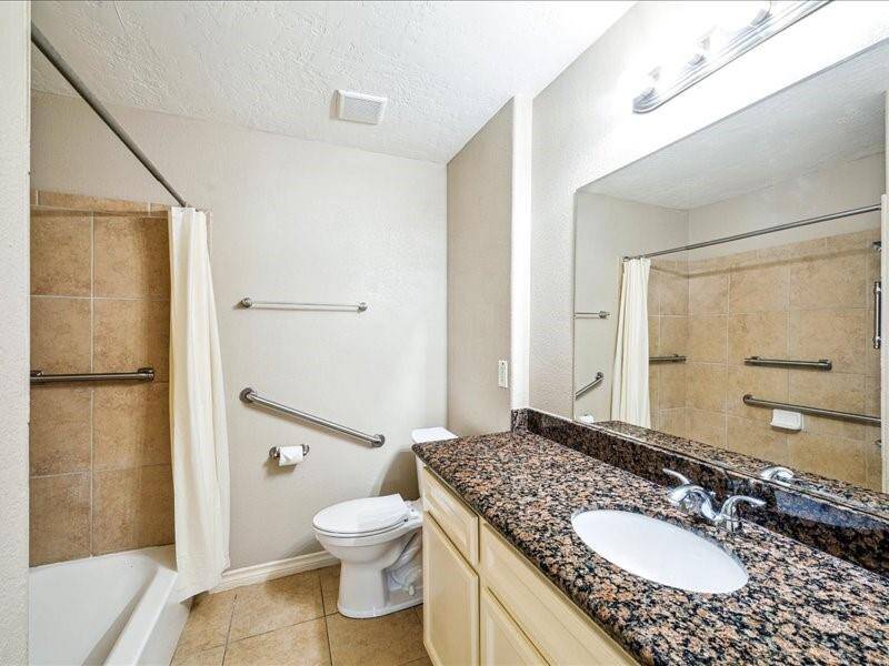 The guest bath features a spacious vanity with a granite countertop and a tub/shower combo accented by a tile surround.