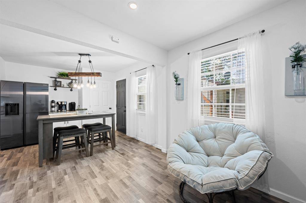 Bright and airy kitchen space with modern fixtures, featuring a sleek stainless steel refrigerator, a cozy seating area, and a stylish island with bar stools. The room is accentuated by natural light from large windows.