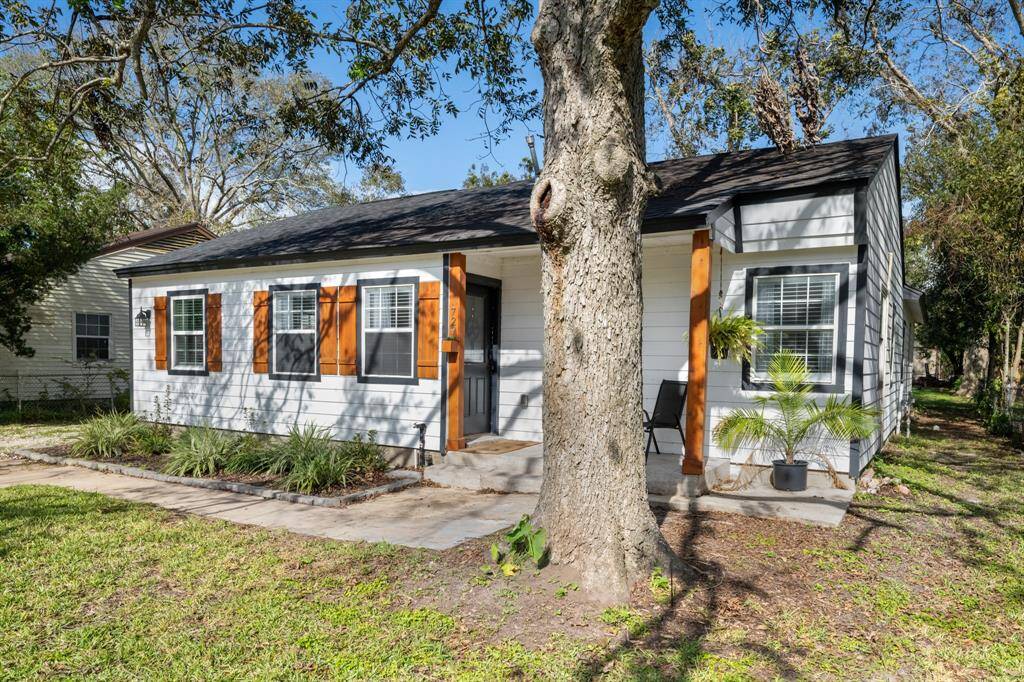 Charming single-story home with a cozy front porch and attractive wood shutters. Surrounded by mature trees, it features a well-maintained lawn and inviting landscaping. Perfect for those seeking a quaint, peaceful setting.