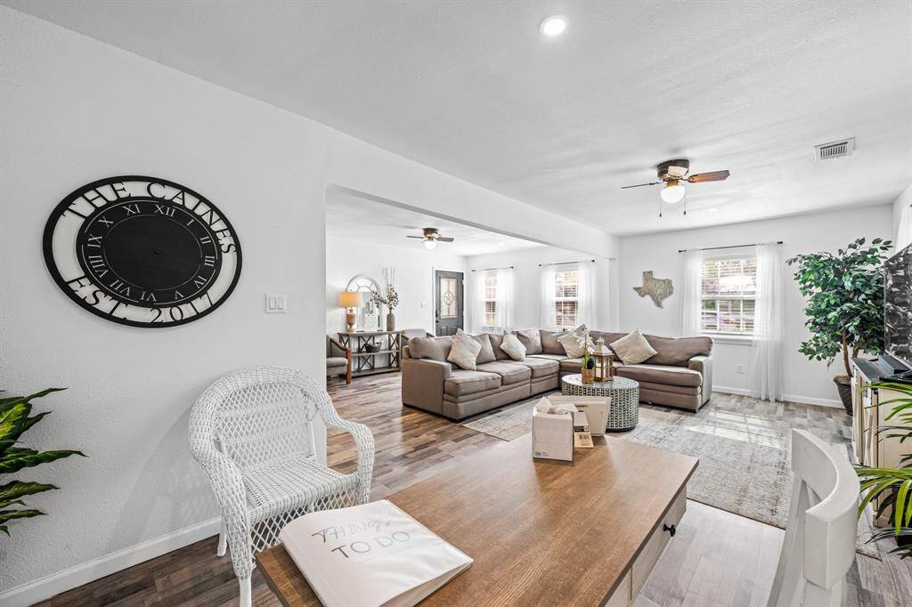 Spacious living area with modern decor, featuring a large sectional sofa, ceiling fans, and abundant natural light. The open layout includes a stylish mix of contemporary and rustic elements, perfect for comfortable living and entertaining.