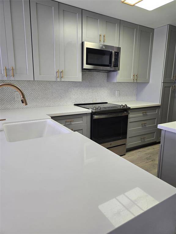 Quartz countertops and a stylish modern backsplash bring a fresh, cheerful vibe to this updated kitchen. Includes a sleek stove, built-in microwave, French-door refrigerator with dual freezer drawers, plus a convenient in-unit washer and dryer.