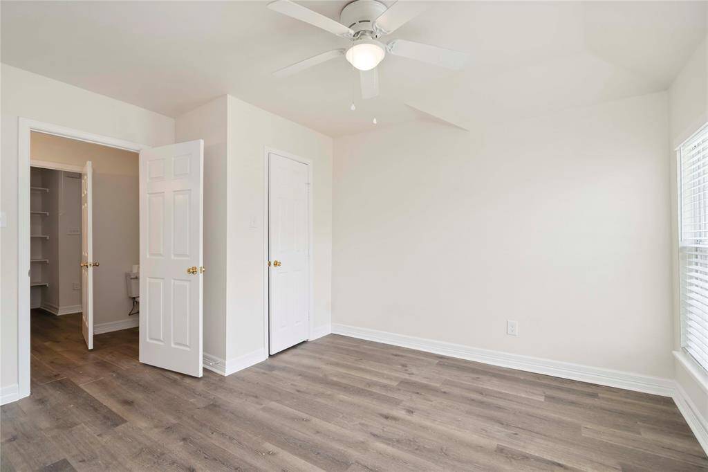Cozy and inviting guest bedroom featuring sleek hardwood floors and ample natural light, perfect for relaxation and comfort.
