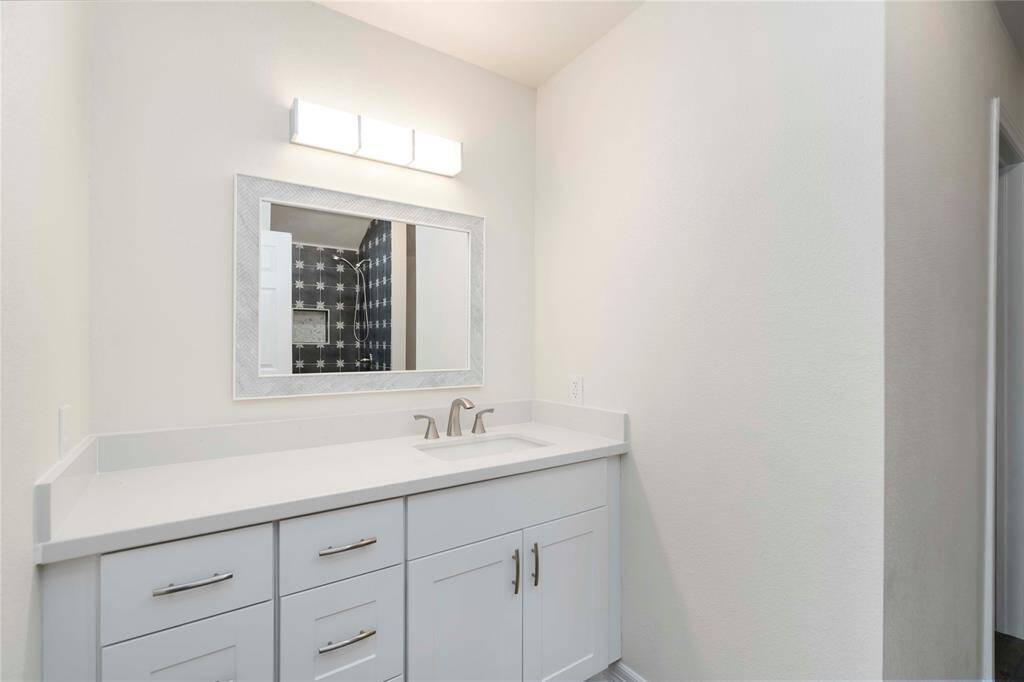 Elegant primary suite vanity with sleek white cabinetry and modern fixtures, perfect for a luxurious touch.