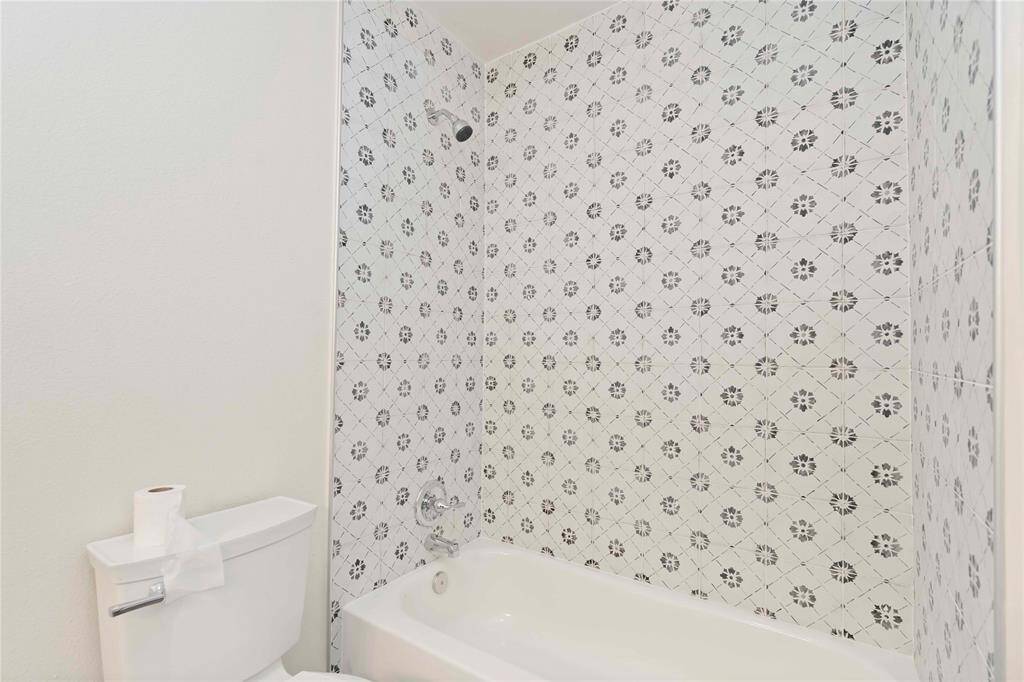 Elegant guest bathroom featuring stylish patterned tile and a modern shower-tub combo.