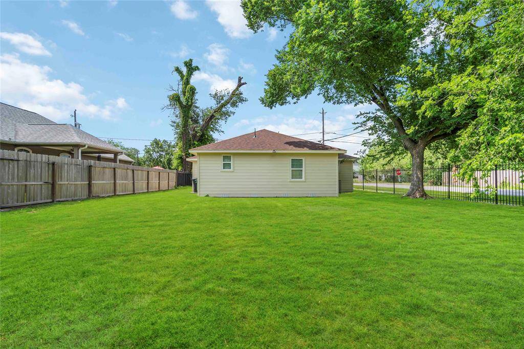 This photo showcases a cozy single-story home with a fenced, spacious grassy backyard, ideal for outdoor activities. The surrounding trees offer shade and privacy.