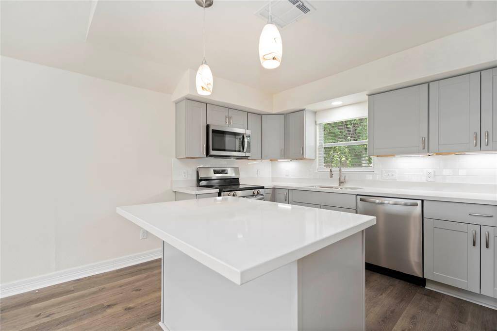 Modern kitchen featuring sleek stainless steel appliances, elegant gray cabinetry, and a spacious island perfect for entertaining.