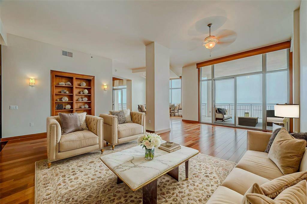 Discover elegance in this spacious family room with handcrafted wood floors, custom lighting, crown molding, built-in bookshelves, and direct balcony access. (AI photo)