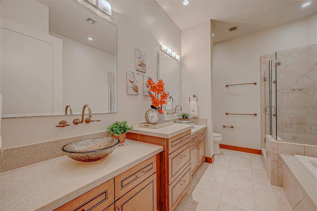 Experience luxury with a sleek glass shower, elegant separate tub, and custom cabinets offering ample storage.