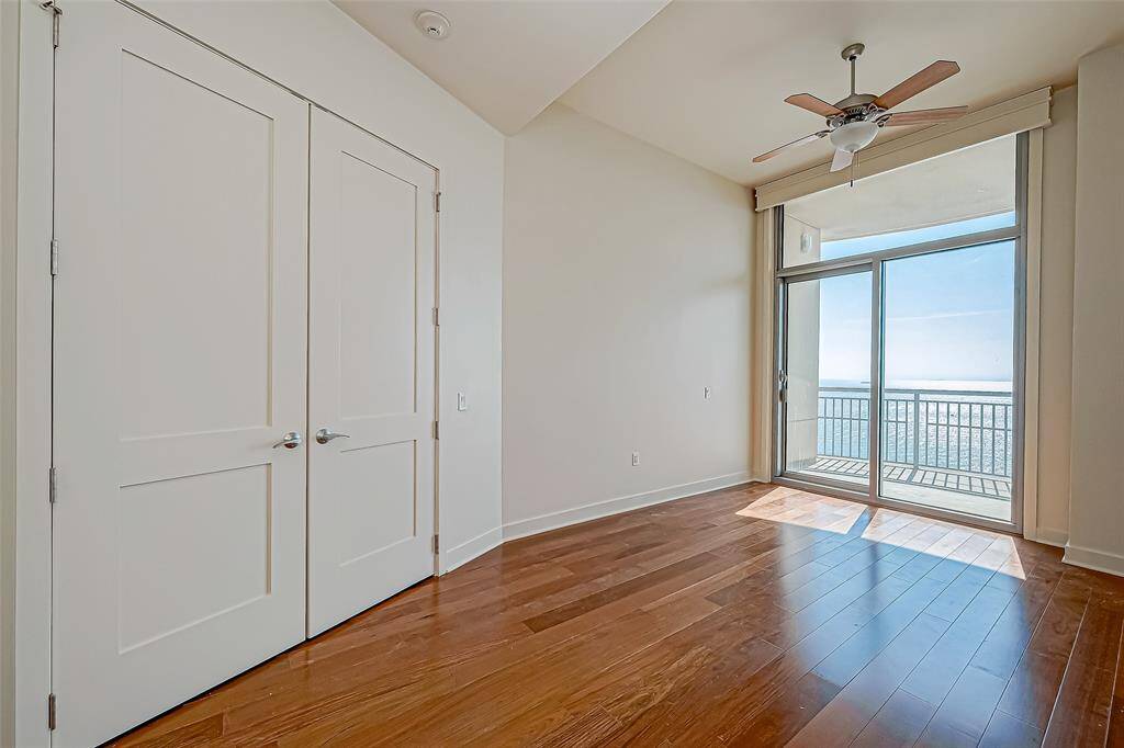 Spacious third bedroom with a private balcony, large closet, room-darkening shades, and stunning new flooring.