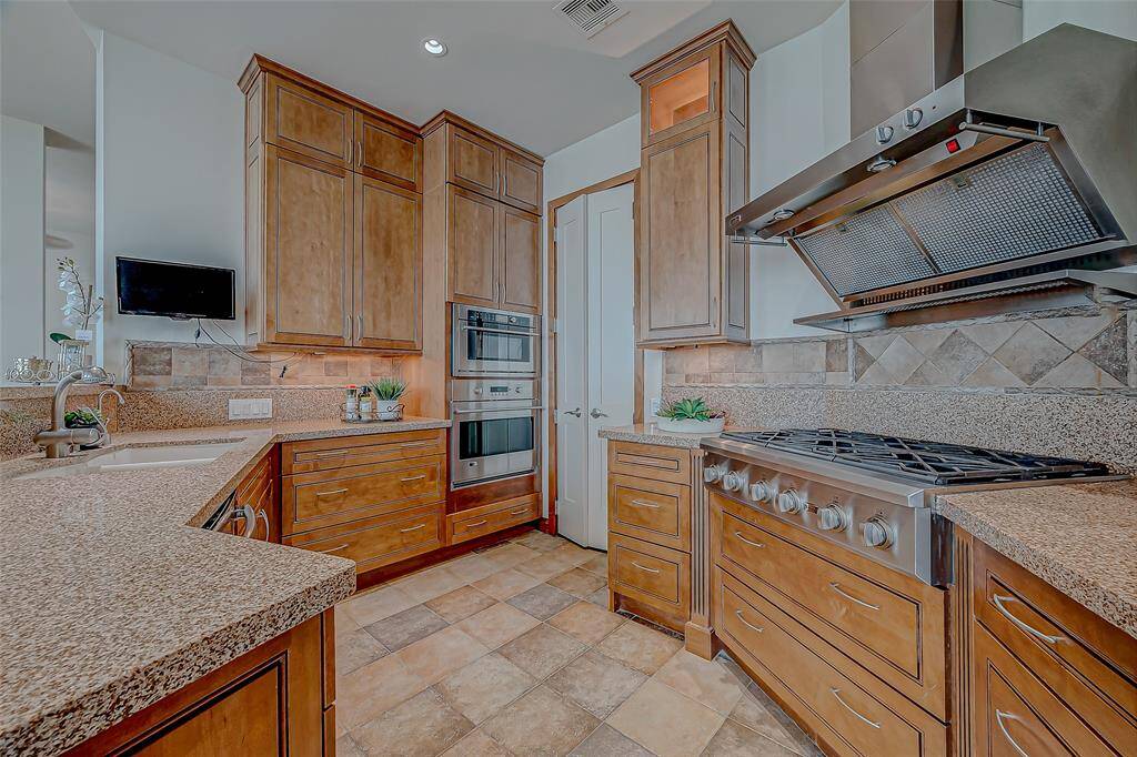 This chef's dream kitchen features a sleek Sub-Zero refrigerator, gas range, custom cabinetry, and elegant granite countertops. Enjoy the convenience of pull-out shelving in every bathroom and the kitchen.