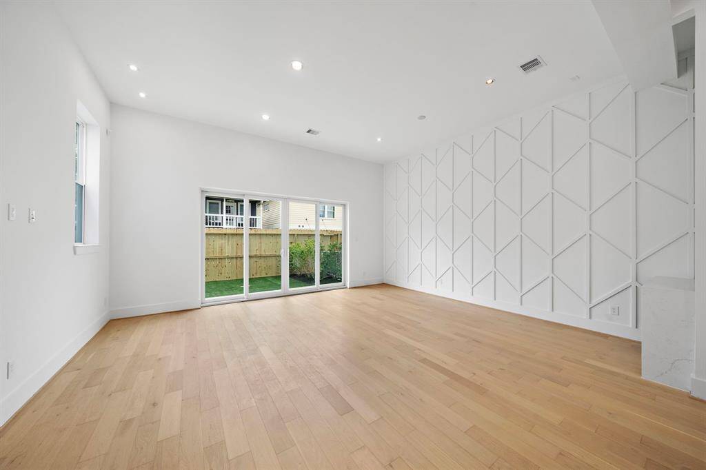 Spacious living/dining room with stylish accent wall. (Photo is of a previously completed home.)