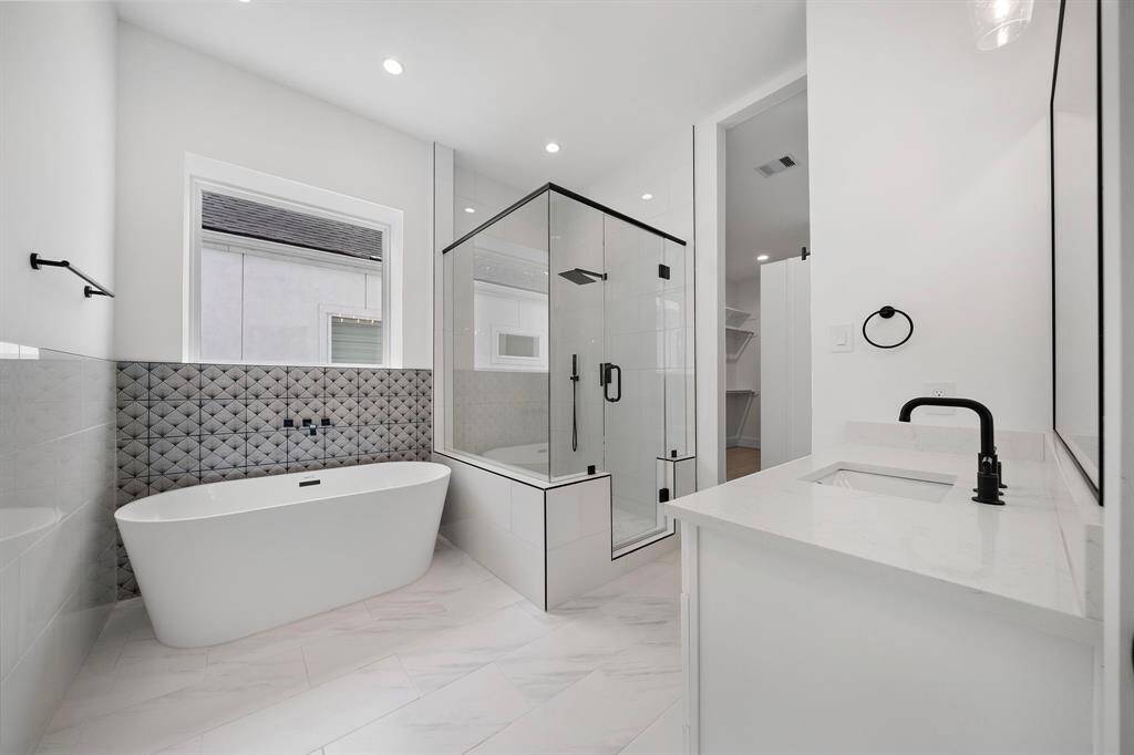 Stylish primary bath with high-end finishes and a freestanding soaking tub. (Photo is of a previously completed home.)