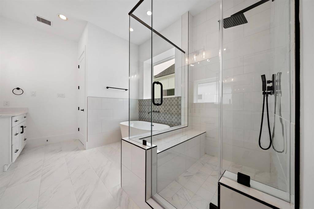 Spa-like primary bath features dual shower heads, shower seat, and tile extending to the ceiling. (Photo is of a previously completed home.)