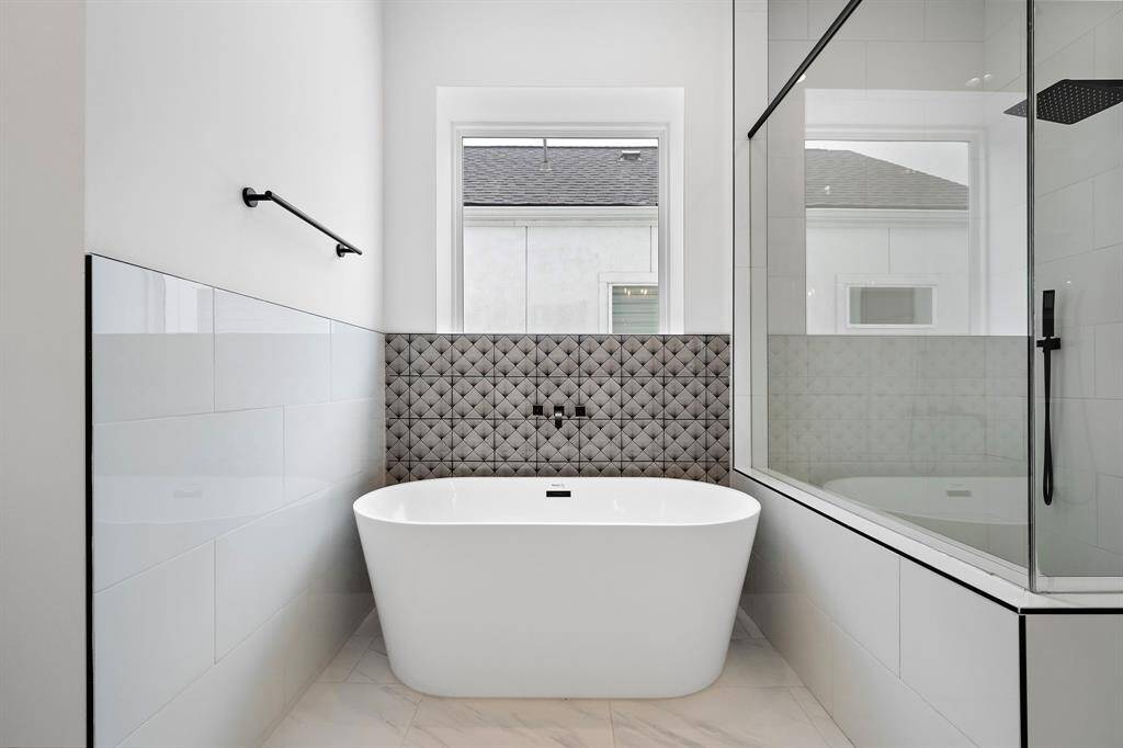 Lovely freestanding soaking tub with decorative tile. (Photo is of a previously completed home.)