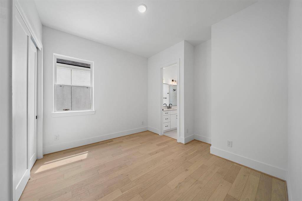 Photo of one of the sizable guest bedrooms with large closet and adjoining bath. (Photo is of a previously completed home that featured upgraded wood flooring.)