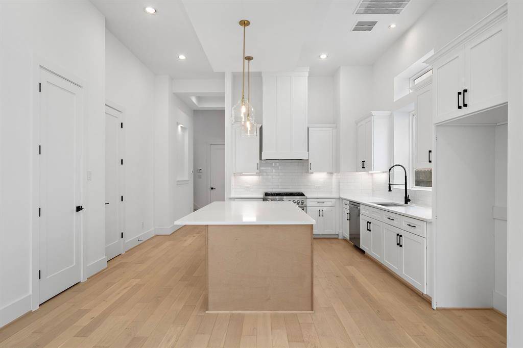 Another view of the impressive island kitchen with stylish pendant lighting and high-end finishes. (Photo is of a previously completed home.)
