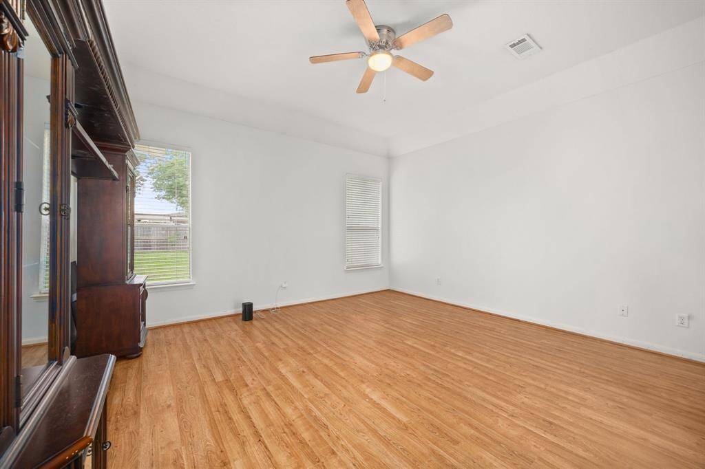 Large primary suite with wood flooring, windows for natural light.