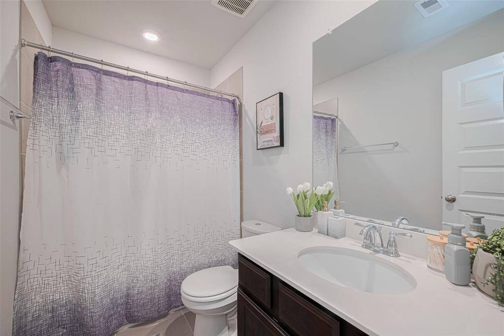 This is upstairs bathroom featuring a modern design with a sleek countertop and sink, a large mirror, and a tub-shower combo with a curtain.