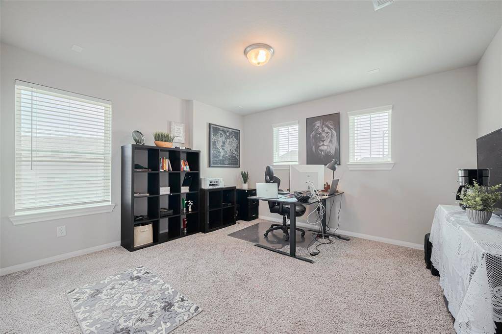 Bright and spacious home office with carpeted flooring and ample natural light from multiple windows. Ideal for remote work or study.