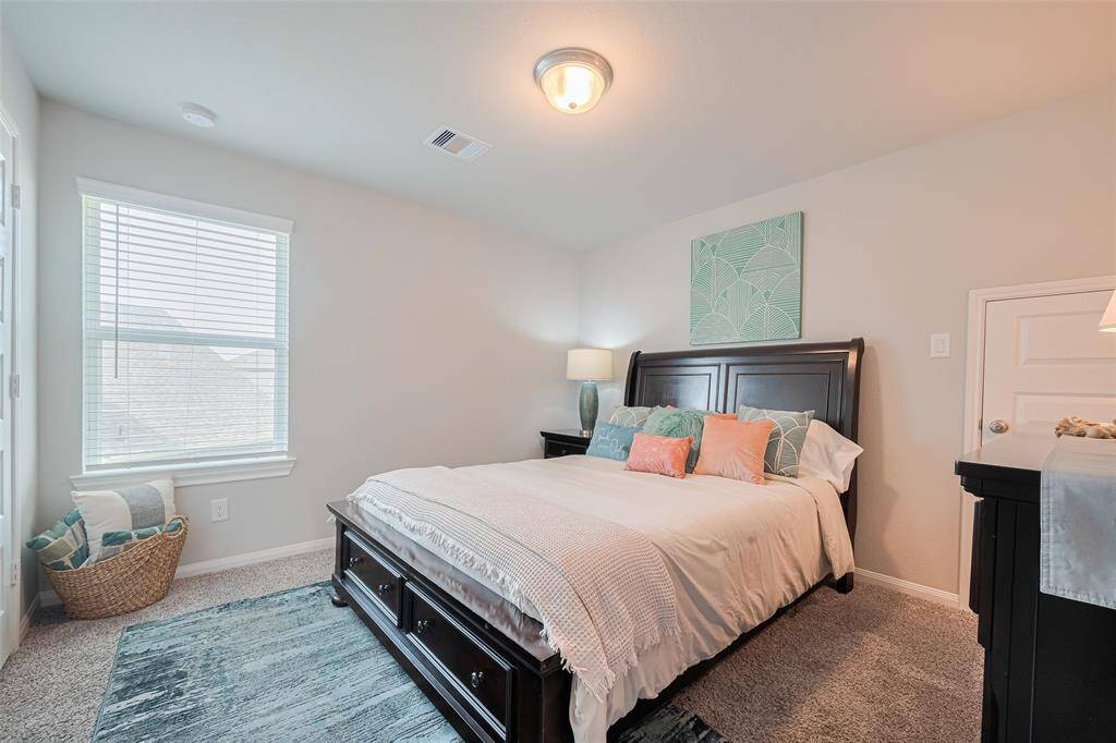 This bright bedroom features soft carpeting, a window with blinds for natural light, and a modern ceiling light fixture.