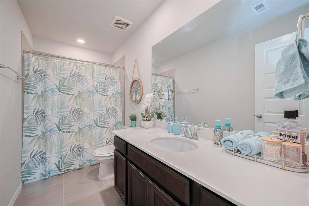 This is another full bathroom featuring a spacious vanity with a large mirror, light countertops, and dark cabinetry and a tub-shower combo.