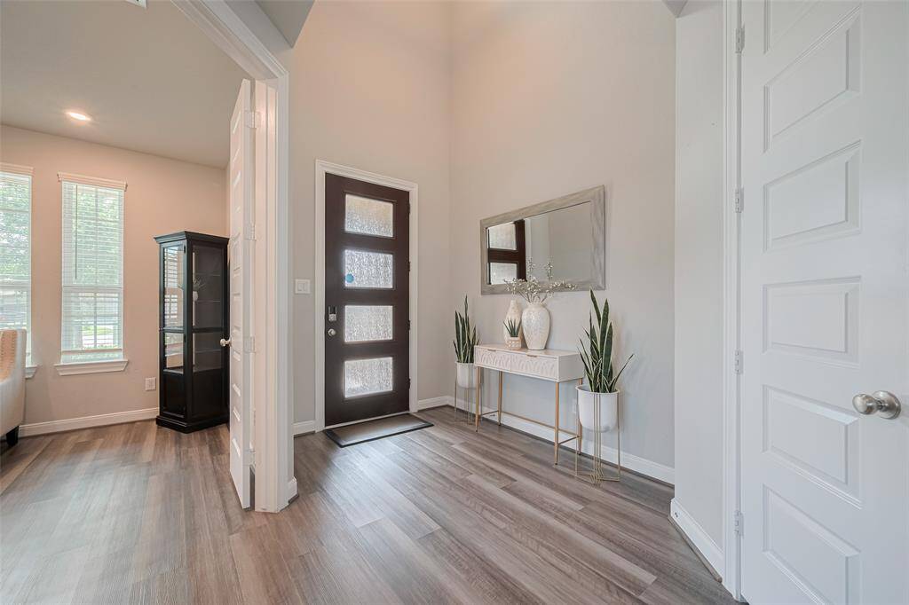 This inviting home entryway features a modern door with frosted glass panels, light color flooring, and neutral walls.