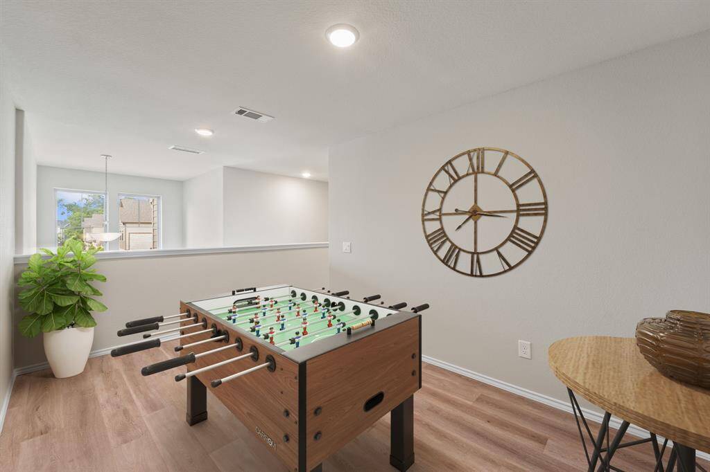 Light and open game room with upstairs landing overlook—flexible enough for gaming, work-from-home setups, or creative use.