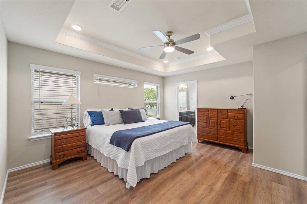 Spacious primary retreat with tray ceiling, updated flooring, and ample natural light—peacefully tucked at the rear of the home.
