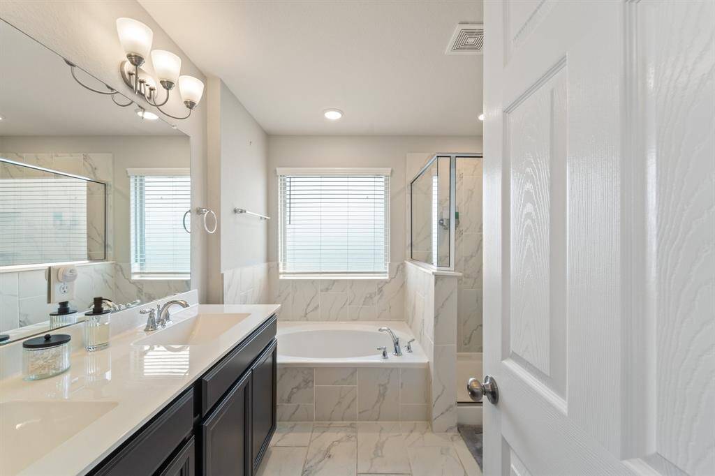 Bright and polished en-suite bath features a walk-in shower, soaking tub, and timeless finishes throughout.