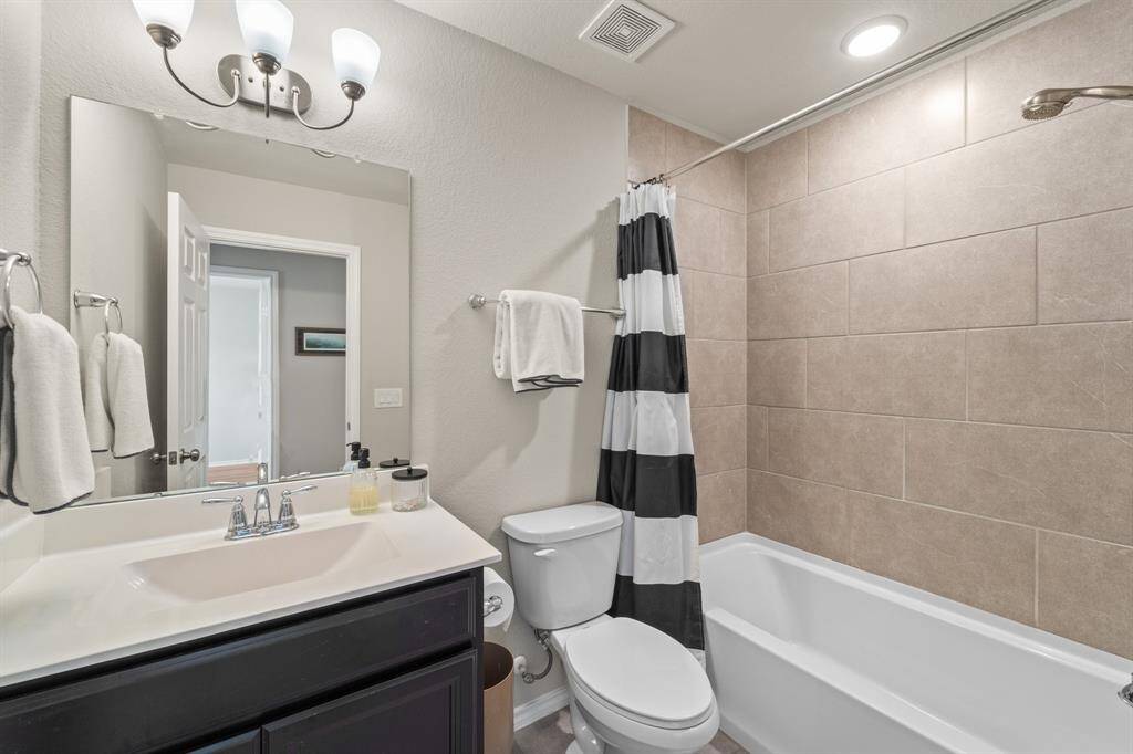 Well-appointed full bathroom upstairs with tile surround shower/tub combo, dark cabinetry, and plenty of counter space.
